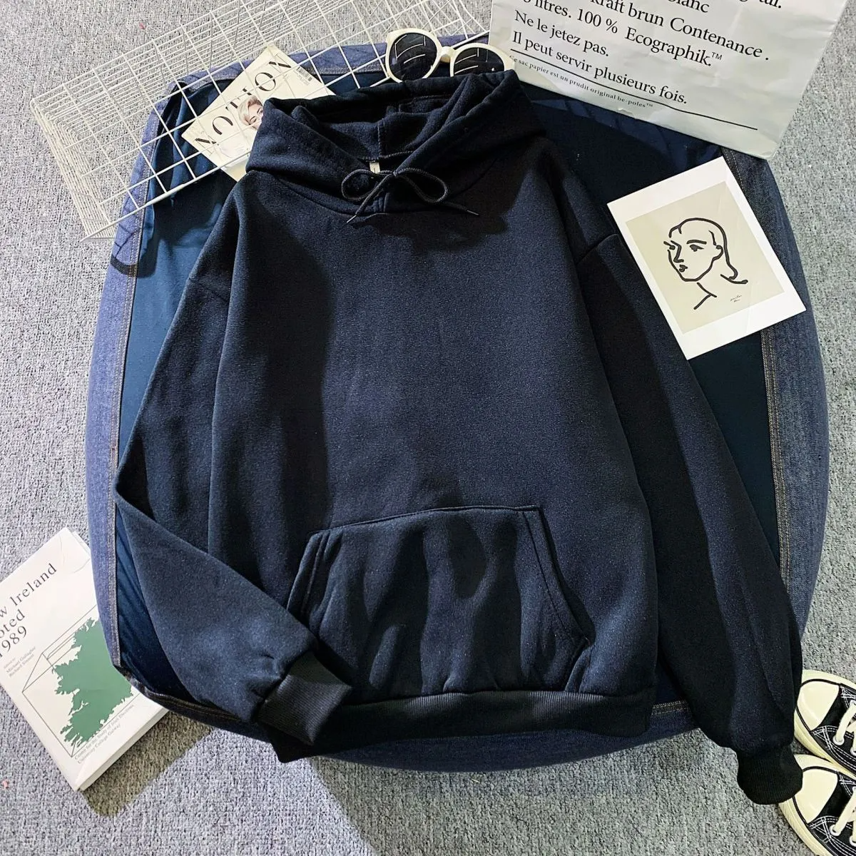 Navy blue hoodie on a textured surface with small items around