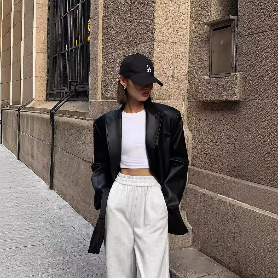 Woman wearing a casual long sleeve lapel coat in black from Multypros paired with white pants and a black cap