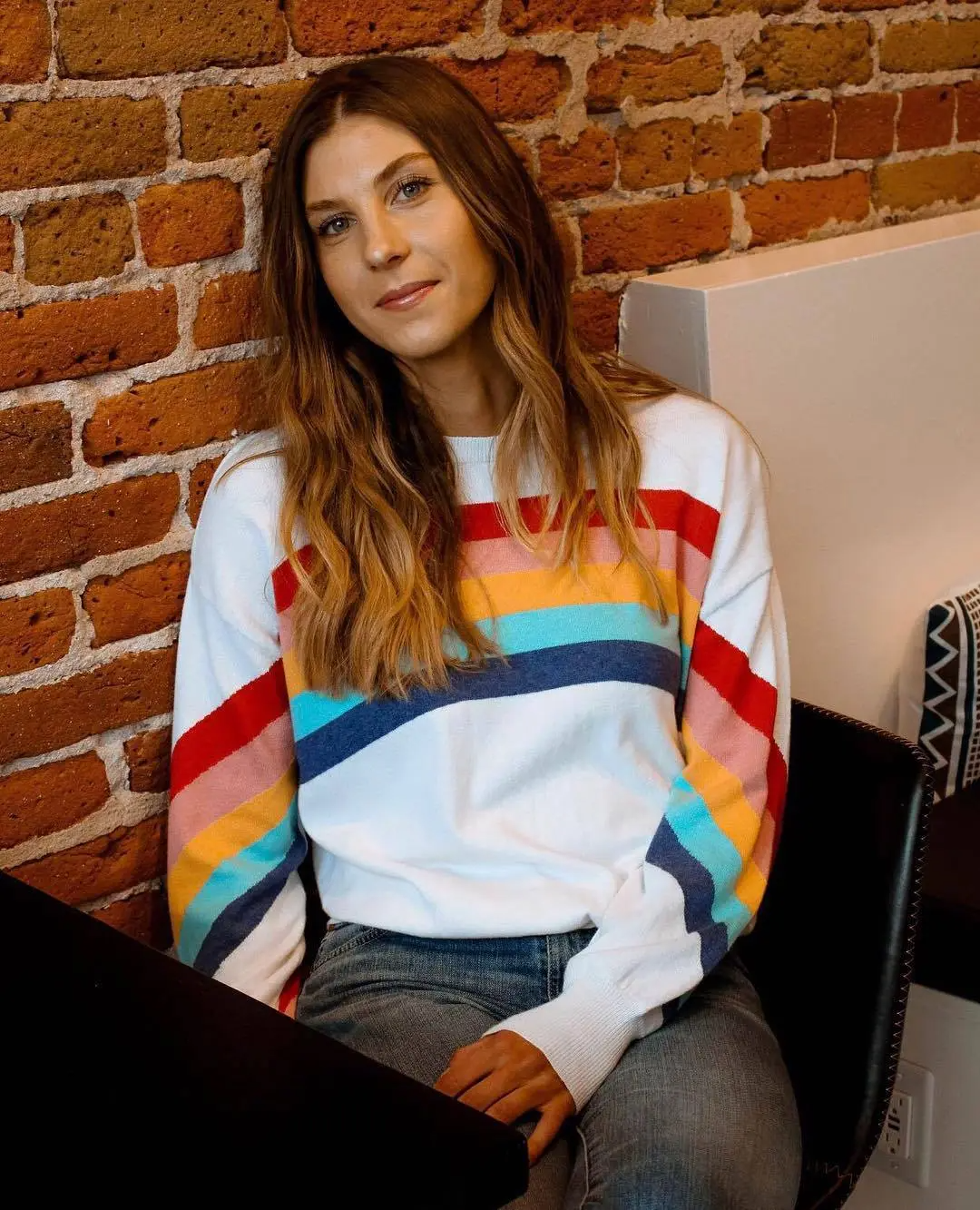 colorful stripes worn by woman sitting against brick wall wholesale casual womens sweaters