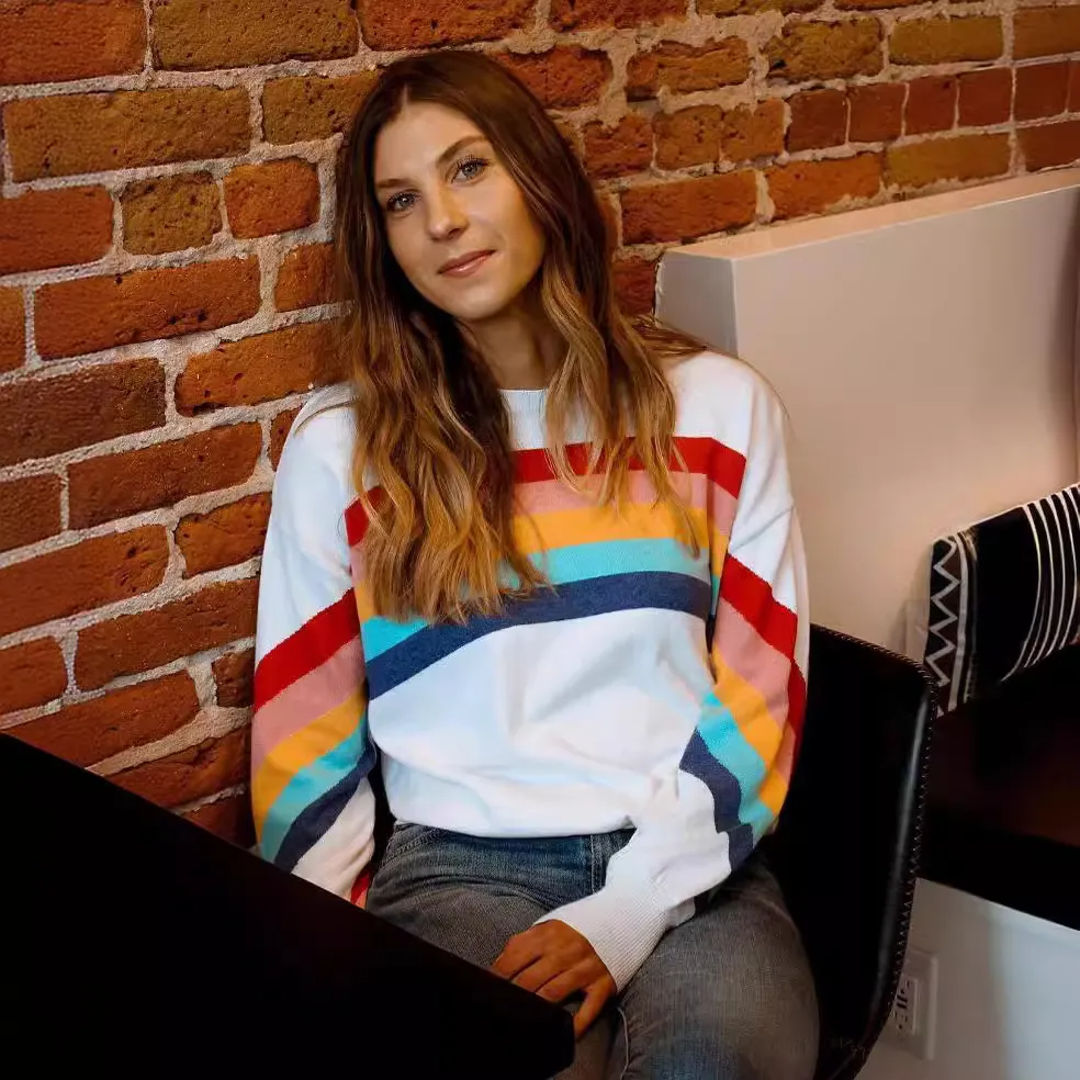 sweatshirt with colorful stripes worn by woman sitting against brick wall wholesale casual womens sweaters