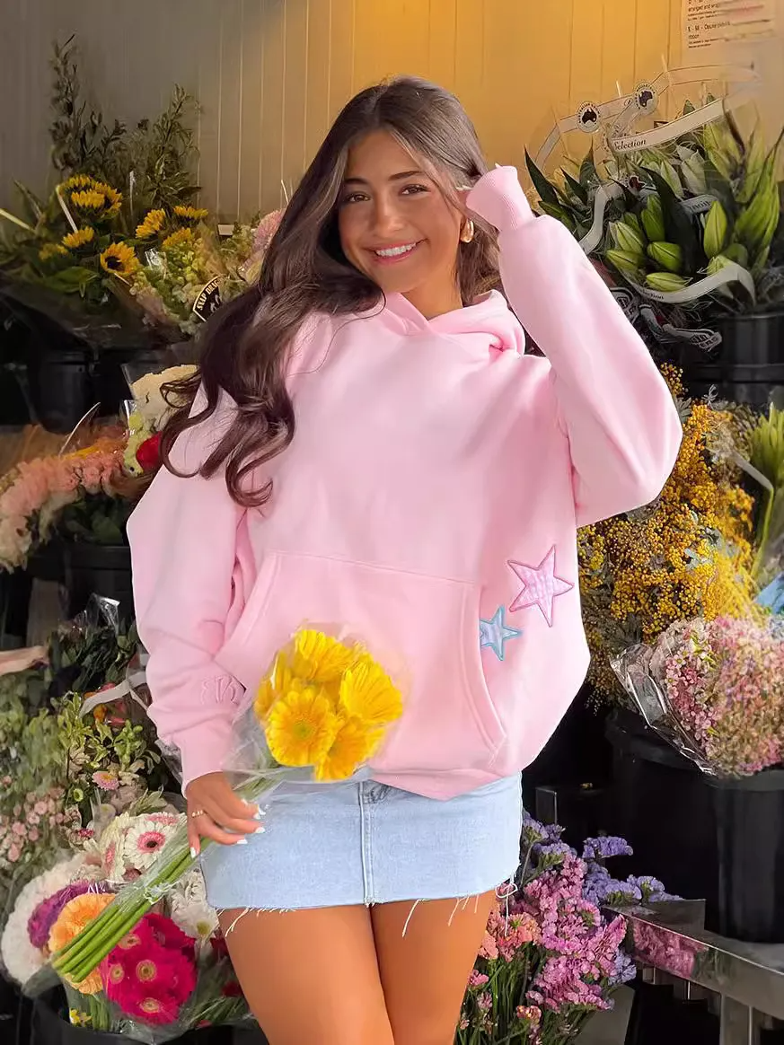 Woman wearing pink fashion hoodies with pocket for women holding yellow flowers standing in flower shop
