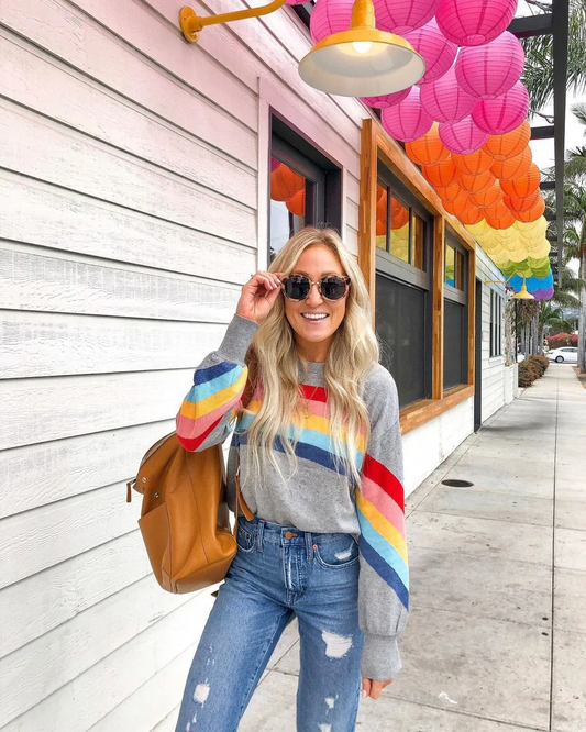 sweatshirt featuring colorful stripes worn by woman with sunglasses and brown backpack wholesale casual women’s sweaters