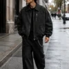 men-wearing-retro-bomber-jacket Men's retro bomber jacket styled for modern streetwear, featuring washed black denim, full zip closure, pointed collar, utility pockets, ribbed waistband and cuffs, and vintage detailing.