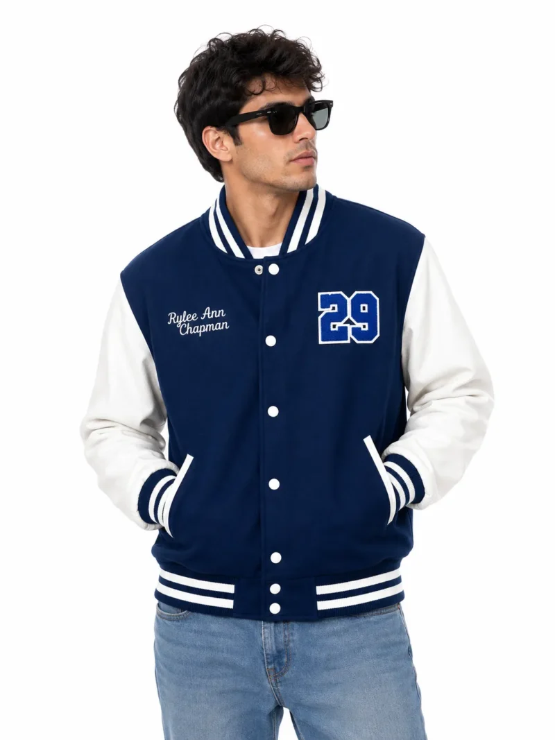 Men’s blue varsity jacket styled for streetwear, featuring white leather sleeves, striped ribbing, snap button closure, custom embroidery and classic varsity-inspired detailing.