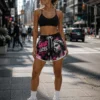 women-wearing-custom-athletic-shorts Close-up of women's custom athletic shorts showing detailed graphic printing, artistic statue artwork, pink lightning effects, elastic waistband, drawstring and contrast side trim.
